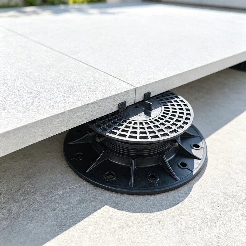 Geteiltes Gummipad auf einem höhenverstellbaren Stelzlager an einer Terrassenplatten-Ecke