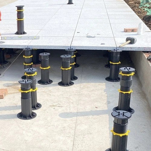 Schwarzes Stelzlager mit gelbem Stellring trägt eine Terrassenplatte